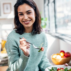 Woman smiling while eating healthy meal at home