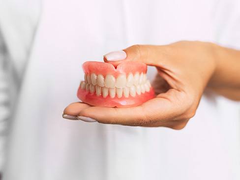 dentist holding dentures in hand 