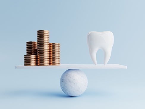 A stack of coins and a model tooth set on a balance beam