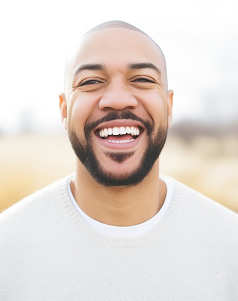 Man in white shirt smiling outside