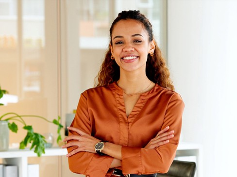 Woman in orange shirt smiling with arms folded