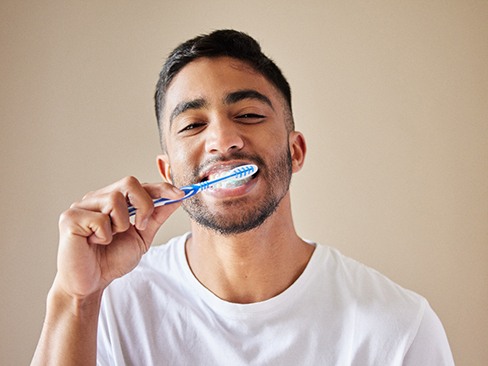 Man in white shirt brushing his teeth